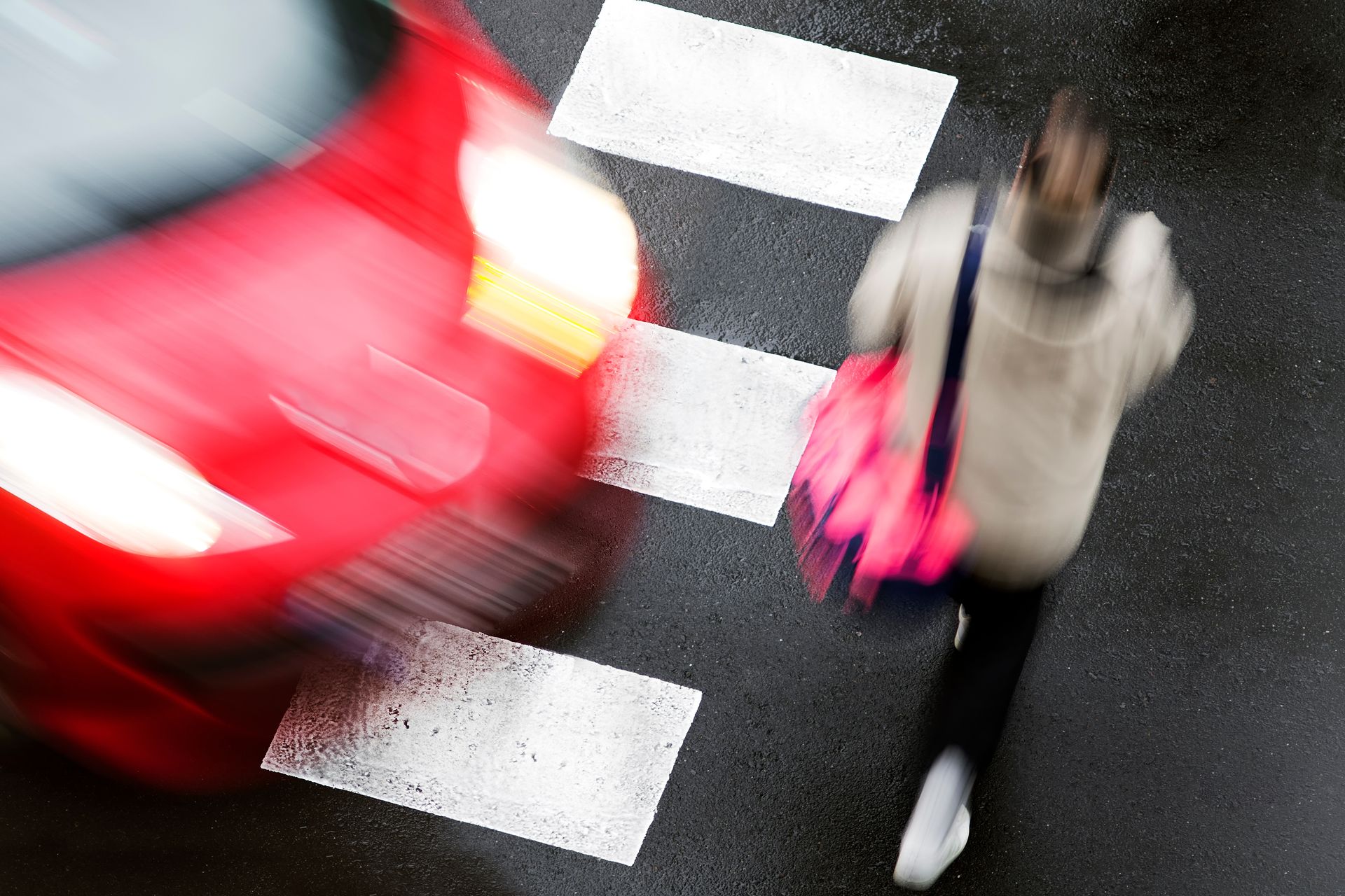 women walking across the crosswalk with an oncoming car bout to hit her.