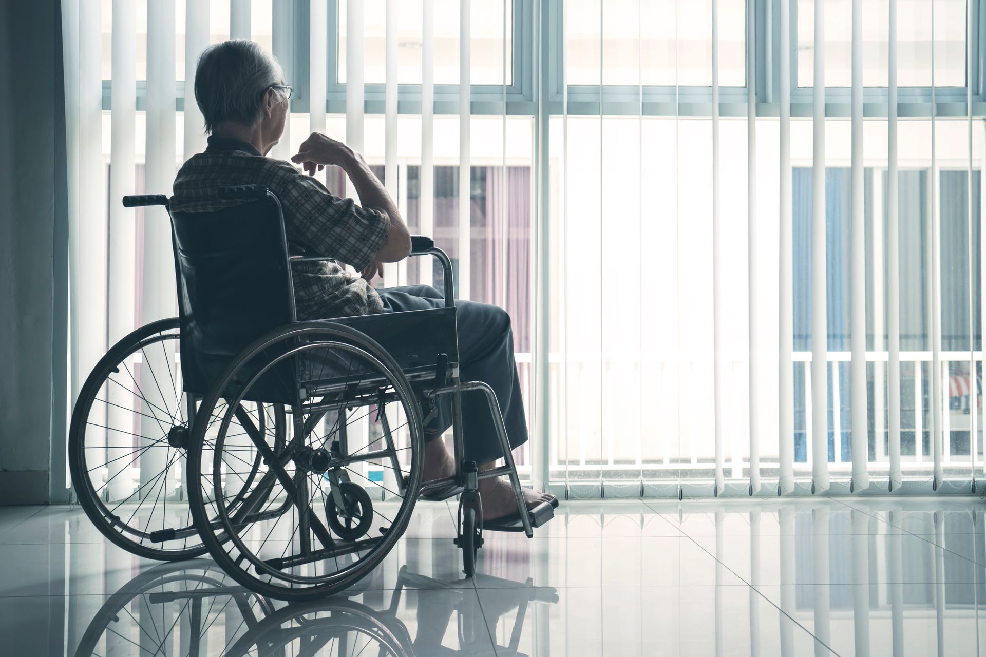 Elderly man looking out the window wondering if he has a case for nursing Home Neglect